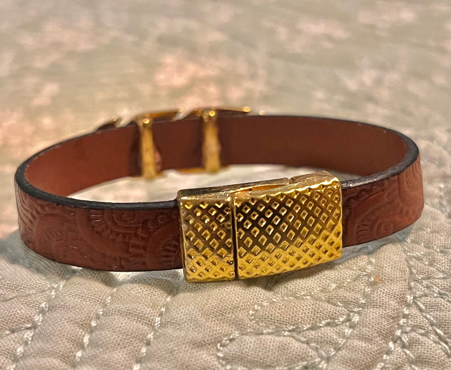 Brunt lær med gulldetaljer.